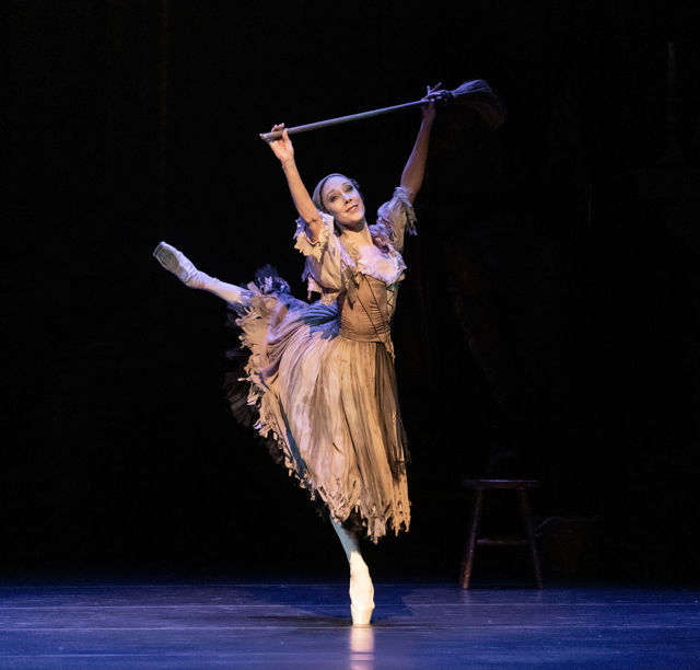 Ballerina på tåspiss som løfter en kost
