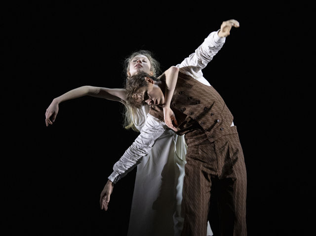 en mann og en kvinne danser sammen, hun i lys kjole og han i dress
