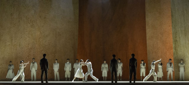 mange dansere kledd i lyse kostymer, fire av dem danser i foran de andre