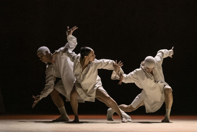 tre dansere i lyse kostymer, kvinne i midten