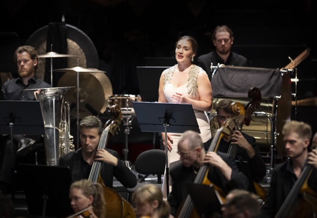 kvinne i lys kjole blant orkestermusikere