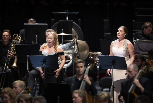 To sangere i konsertkjoler blant orkestermusikere