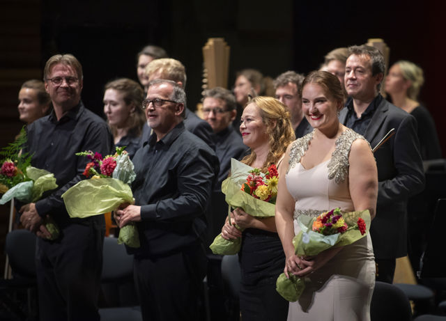 Smilende mennesker med blomsterbuketter på konsertscene