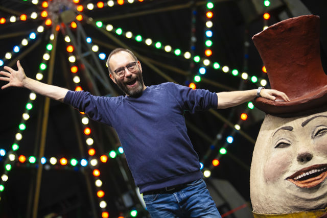 Mann ved siden av stor Humpty Dumpty-figur foran pariserhjul 
